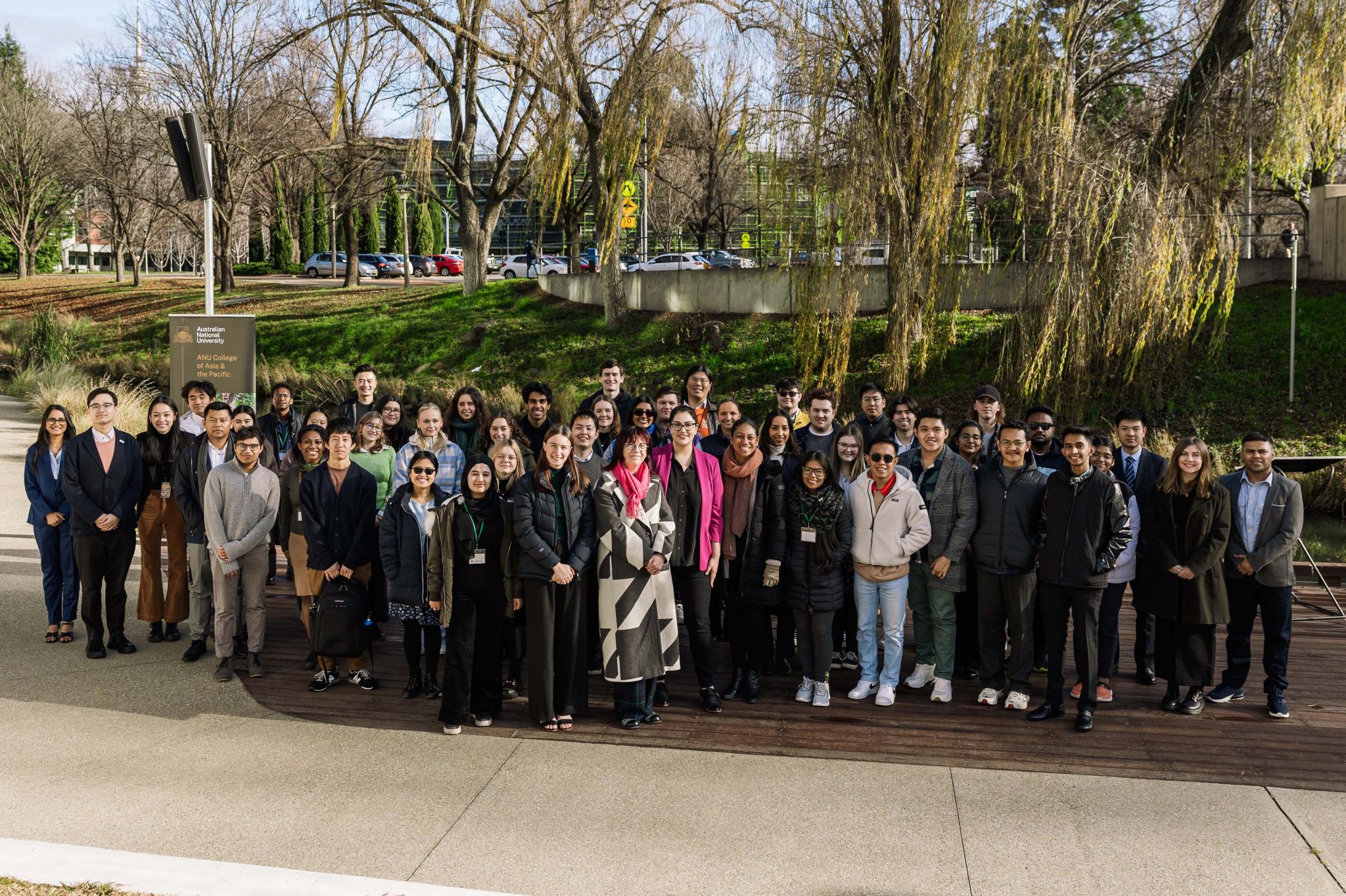 Asia Pacific Week delegates, panellists and organising committee members standing in front of trees for a group photo