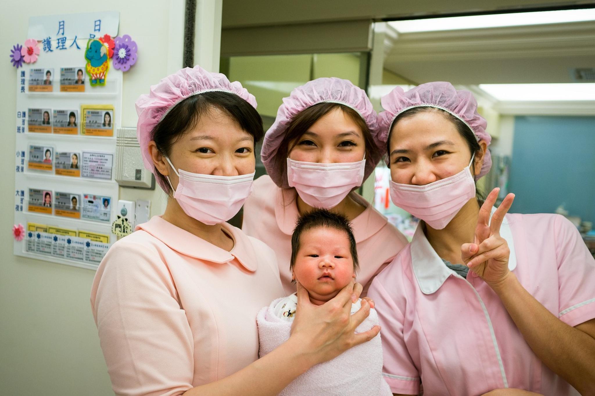 Three Japanese nurses and an infant pose for a photo