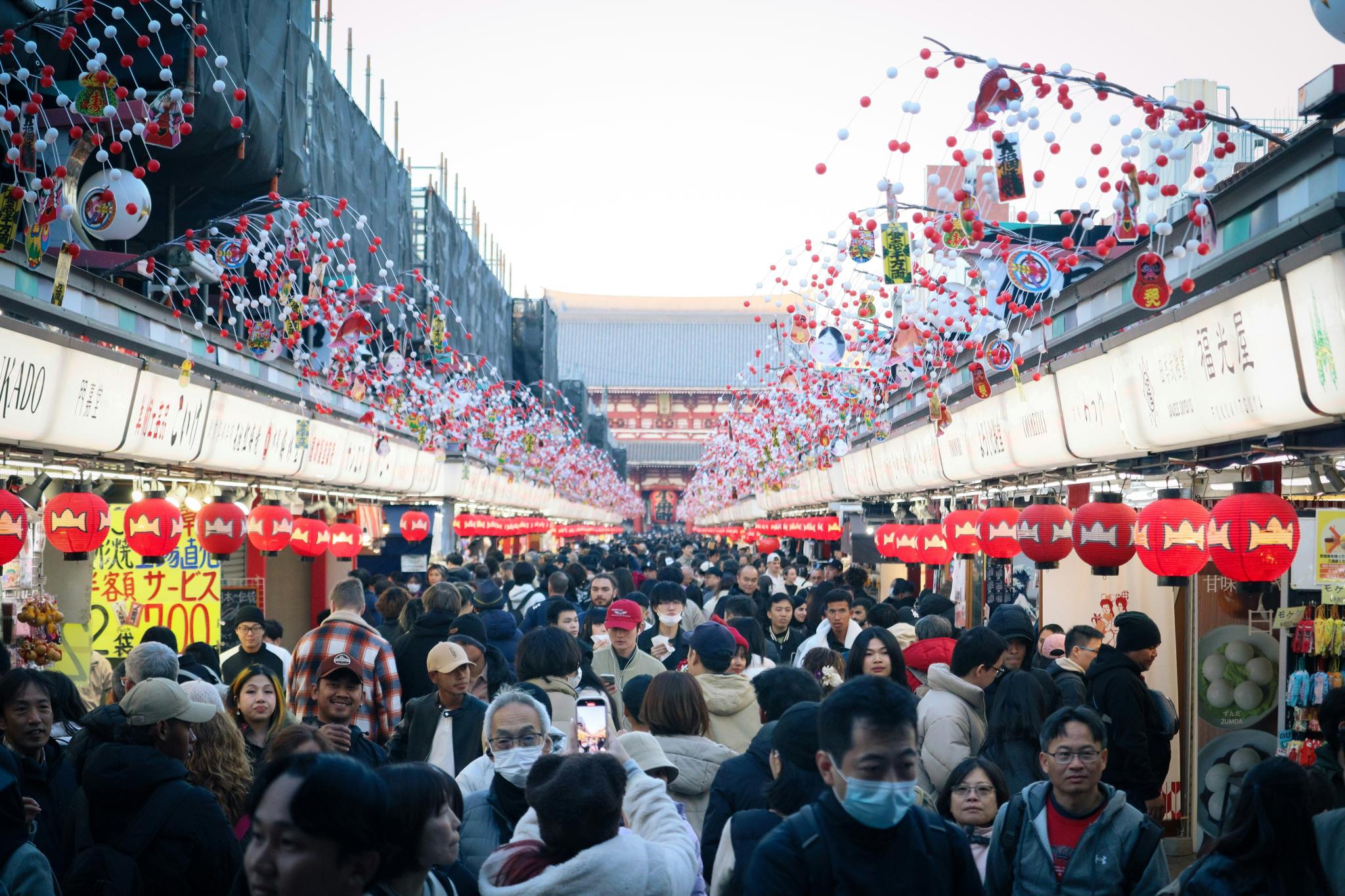 A bustling crowd walks through a decorated street in Sensō-ji, Tokyo, Japan.
