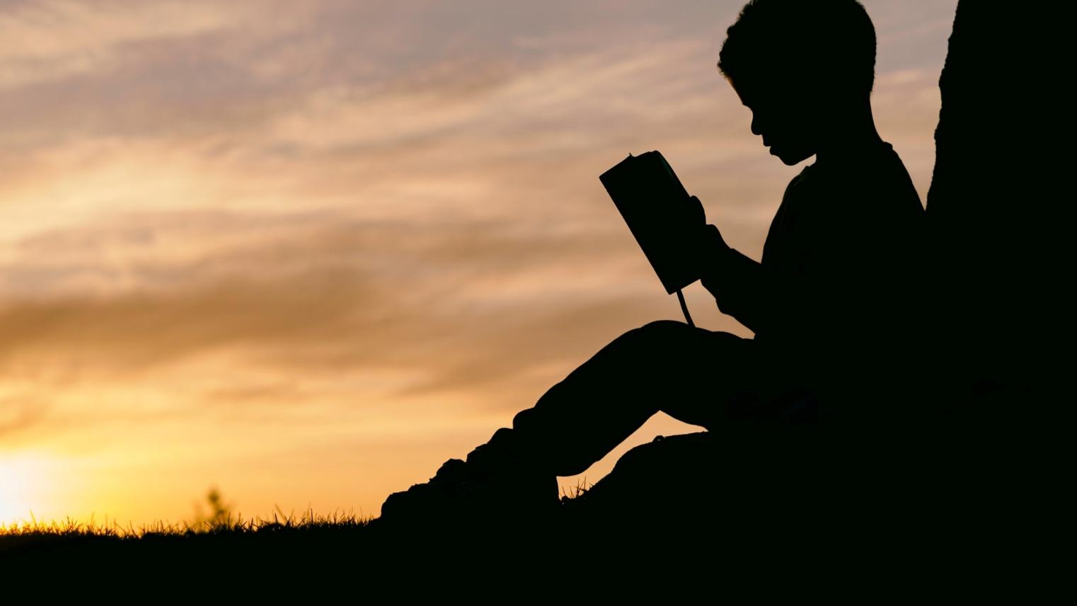 Photo by Aaron Burden on Unsplash Silhoette of a boy reading a book
