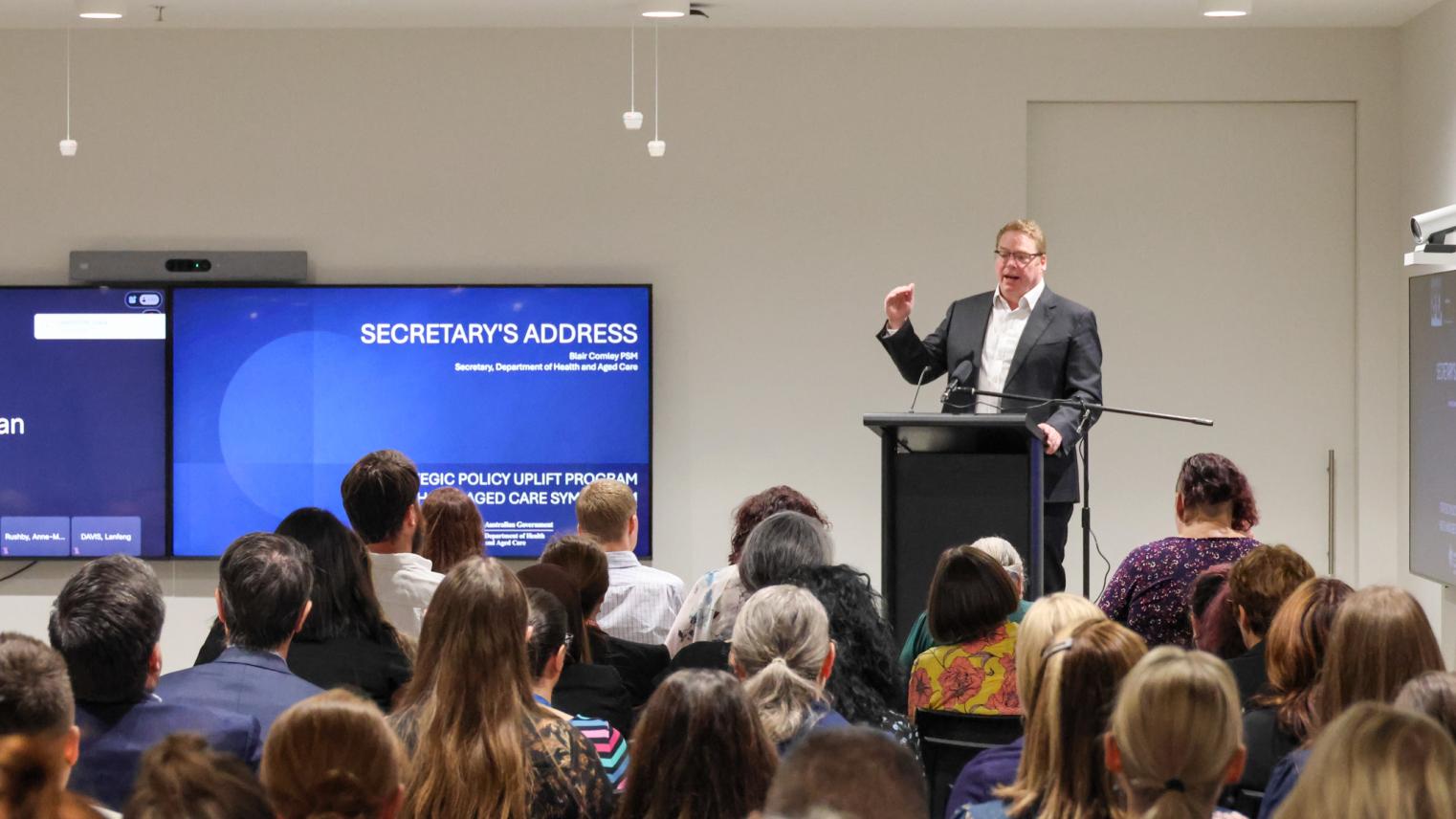 Blair Comley PSM, Secretary of the Department of Health and Aged Care at the Symposium Blair Comley PSM, Secretary of the Department of Health and Aged Care