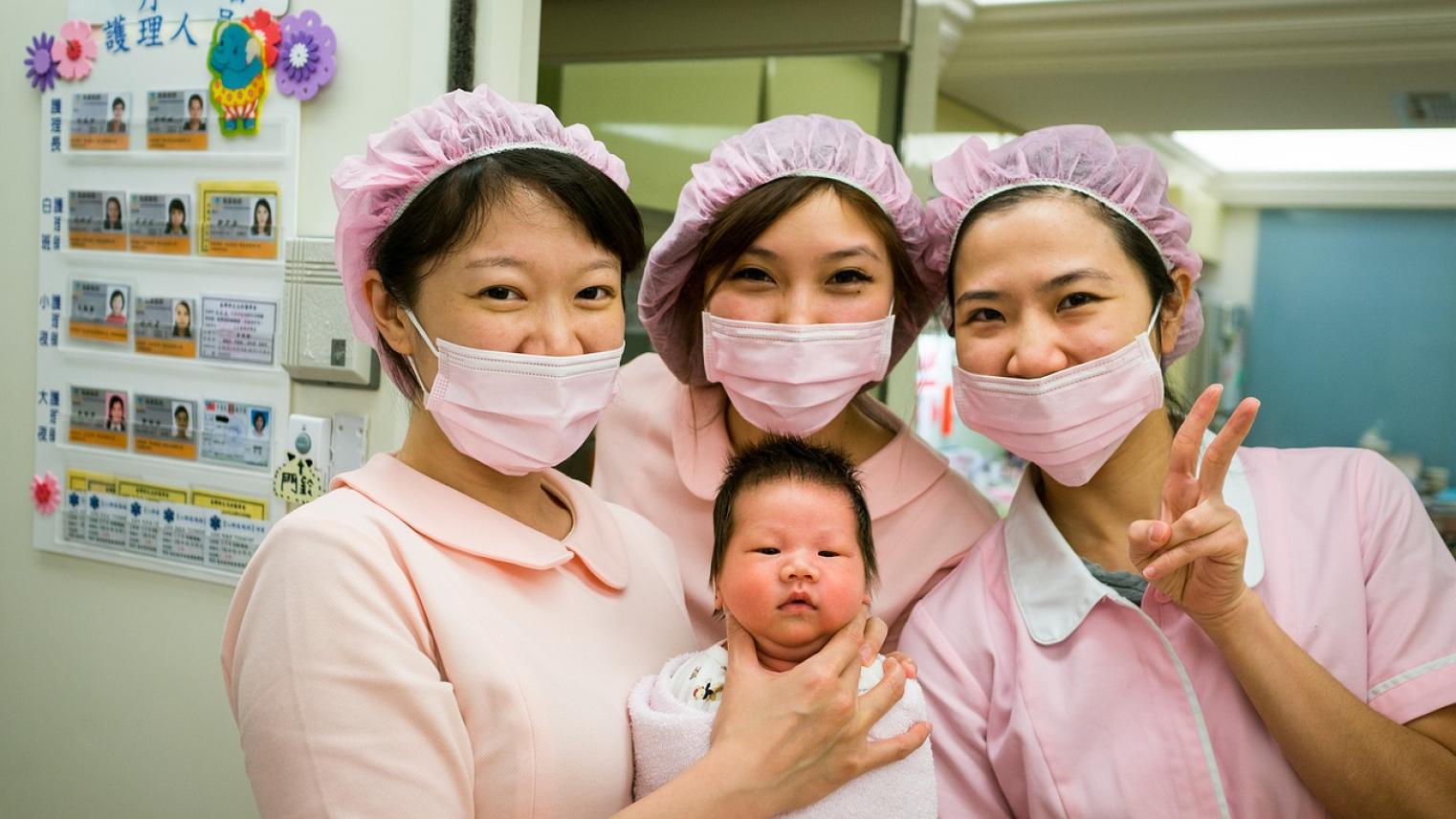 Three Japanese nurses and an infant pose for a photo